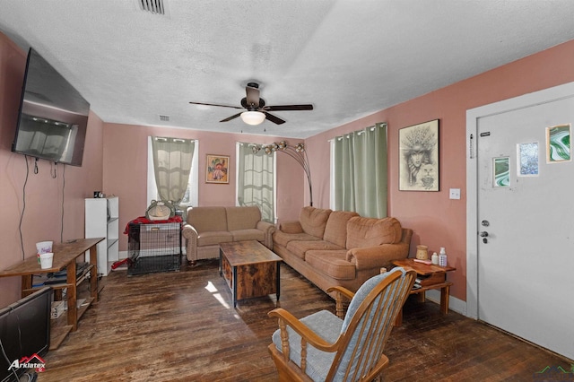 living room featuring ceiling fan, dark hardwood / wood-style flooring, and a textured ceiling