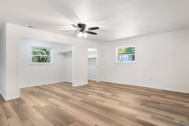 spare room featuring ceiling fan, a healthy amount of sunlight, a textured ceiling, and light hardwood / wood-style floors