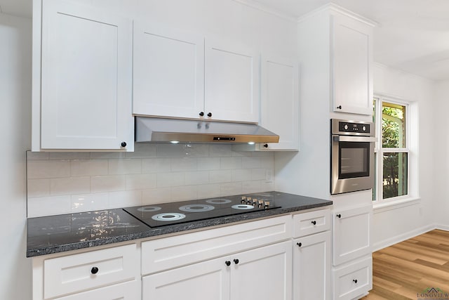 kitchen featuring decorative backsplash, black electric stovetop, stainless steel oven, light hardwood / wood-style floors, and white cabinetry