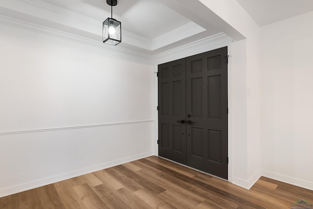 foyer featuring hardwood / wood-style floors, a raised ceiling, and crown molding