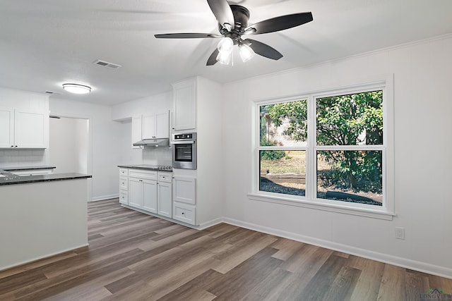 kitchen featuring decorative backsplash, stainless steel oven, and white cabinets