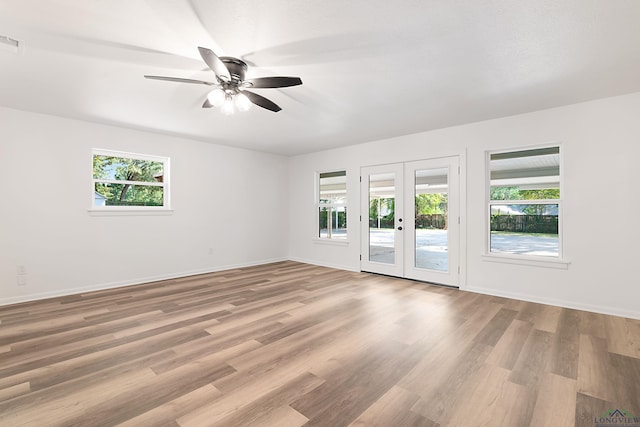 spare room featuring french doors, light hardwood / wood-style flooring, ceiling fan, and a healthy amount of sunlight