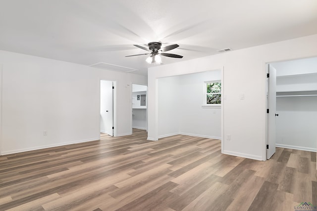 unfurnished bedroom with wood-type flooring, a closet, a spacious closet, and ceiling fan