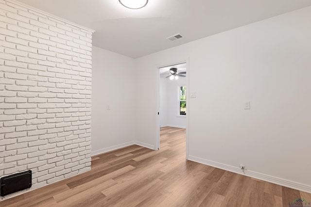 unfurnished room with brick wall and light hardwood / wood-style flooring