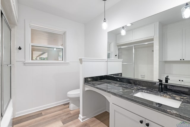 bathroom featuring hardwood / wood-style floors, vanity, toilet, and a shower with door