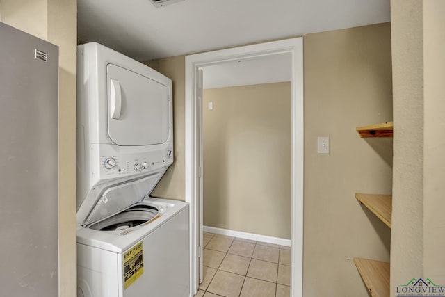 laundry area with light tile patterned floors and stacked washing maching and dryer