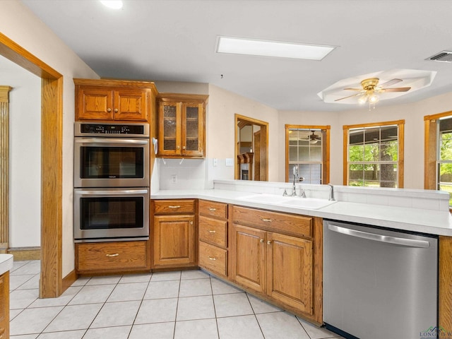 kitchen with sink, ceiling fan, appliances with stainless steel finishes, light tile patterned flooring, and kitchen peninsula