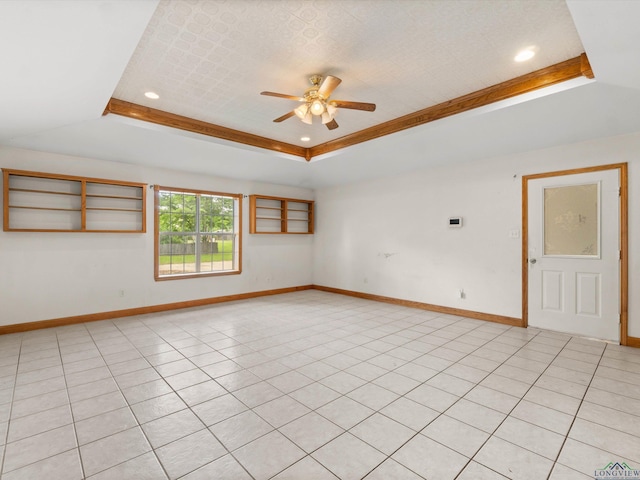 empty room with ceiling fan, light tile patterned floors, and a tray ceiling