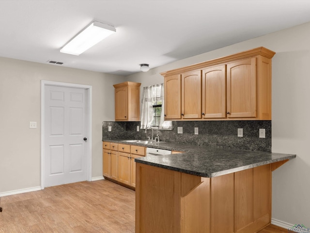 kitchen with dishwashing machine, kitchen peninsula, sink, and light hardwood / wood-style flooring