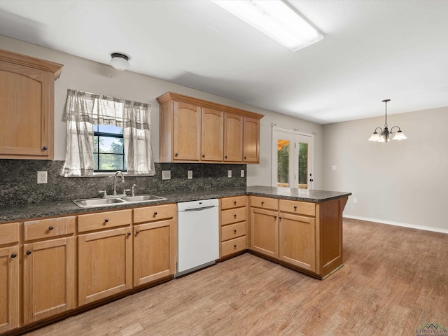 kitchen featuring kitchen peninsula, white dishwasher, sink, pendant lighting, and a notable chandelier