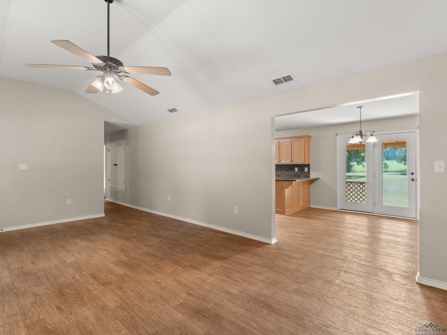 unfurnished living room featuring ceiling fan with notable chandelier, wood-type flooring, and lofted ceiling