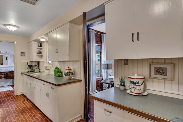 603 E Melton, Longview, TX 75602 - kitchen with a sink, dark countertops, brick patterned floors, and white cabinetry