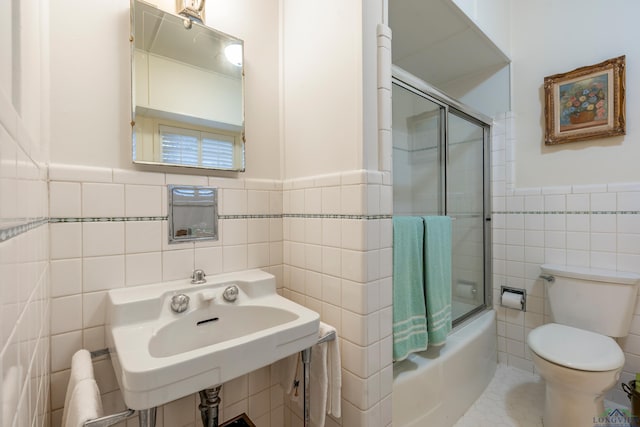 603 E Melton, Longview, TX 75602 - bathroom with tile walls, toilet, wainscoting, enclosed tub / shower combo, and a sink