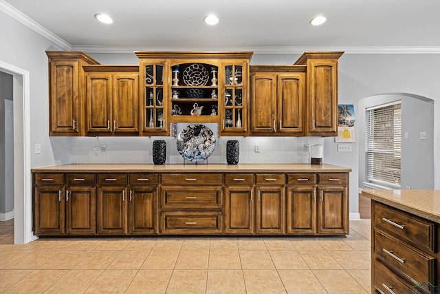 kitchen featuring backsplash, light tile patterned floors, and crown molding