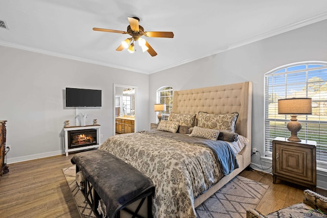 bedroom featuring hardwood / wood-style floors, ceiling fan, ornamental molding, and ensuite bath