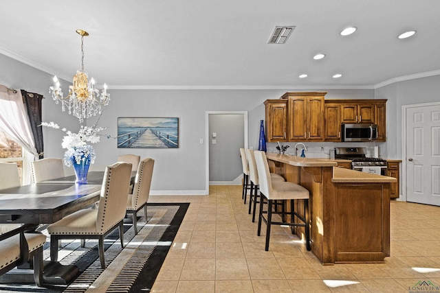 kitchen featuring an inviting chandelier, crown molding, hanging light fixtures, light tile patterned floors, and appliances with stainless steel finishes