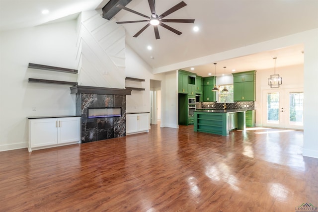 unfurnished living room with french doors, ceiling fan with notable chandelier, beam ceiling, high vaulted ceiling, and a premium fireplace