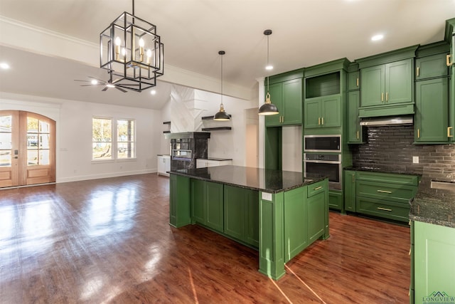 kitchen featuring appliances with stainless steel finishes, dark stone counters, decorative light fixtures, green cabinetry, and a center island