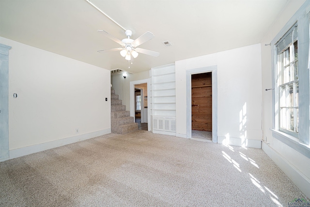 empty room featuring carpet, ceiling fan, and built in shelves