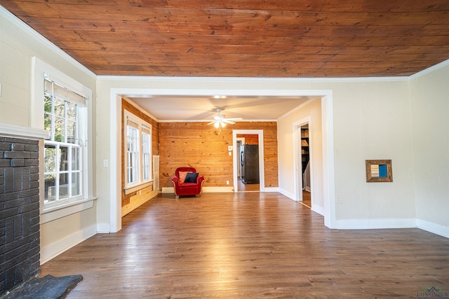 unfurnished living room with a brick fireplace, ornamental molding, dark wood-type flooring, wooden walls, and wooden ceiling