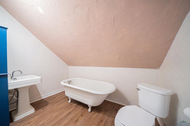 bathroom with a bathing tub, toilet, lofted ceiling, and hardwood / wood-style flooring