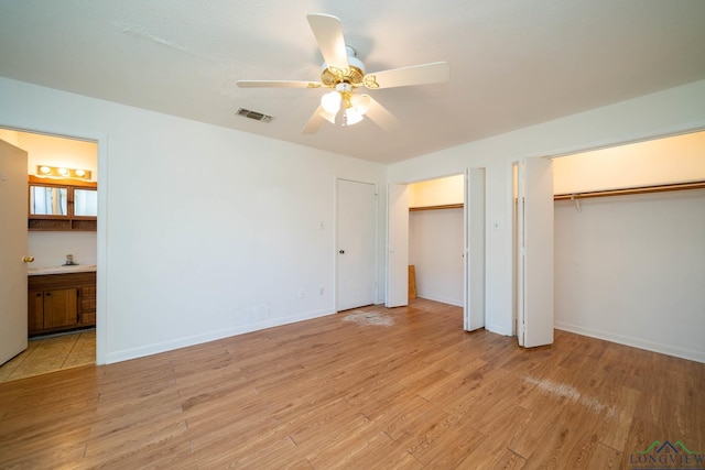 unfurnished bedroom featuring ceiling fan, two closets, connected bathroom, and light hardwood / wood-style floors