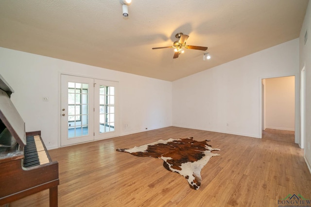 living room with ceiling fan, lofted ceiling, a textured ceiling, and light hardwood / wood-style flooring