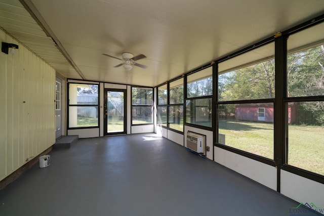 unfurnished sunroom featuring ceiling fan and a wall mounted AC