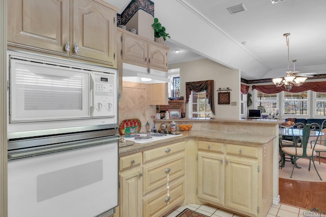 kitchen featuring backsplash, kitchen peninsula, white appliances, light tile patterned floors, and a chandelier