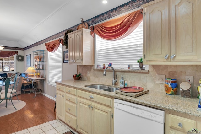 kitchen with sink, backsplash, vaulted ceiling, white dishwasher, and light tile patterned floors