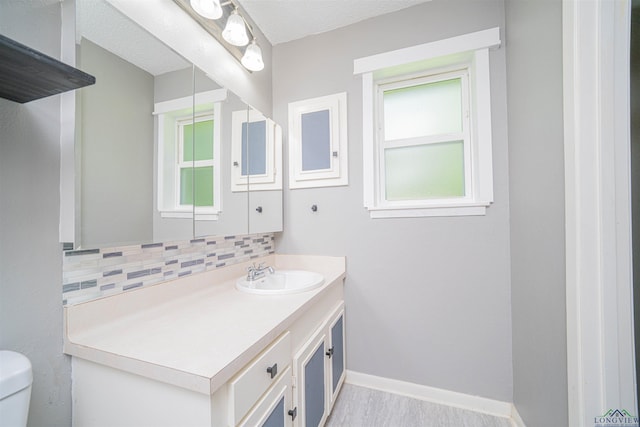 4525 Surratt Rd, Longview, TX 75604 - bathroom with toilet, vanity, tasteful backsplash, baseboards, and wood finished floors