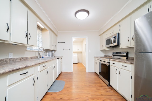 105 Sherwood Dr, Longview, TX 75605 - kitchen featuring ornamental molding, stainless steel appliances, a sink, washer / dryer, and light wood-style floors