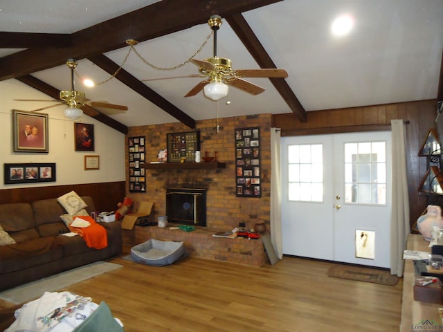 living room with lofted ceiling with beams, ceiling fan, french doors, and wooden walls