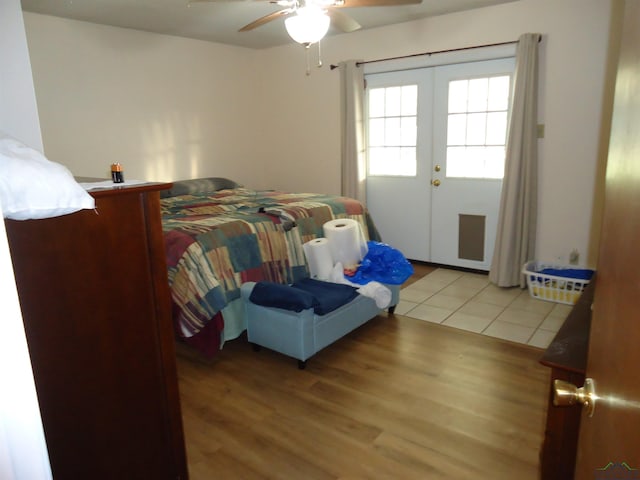 bedroom featuring french doors, light wood-type flooring, and a ceiling fan