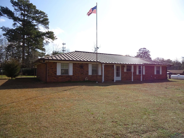 ranch-style home featuring a standing seam roof, brick siding, metal roof, and a front lawn