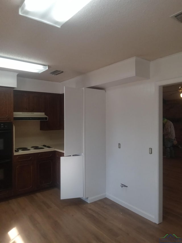 kitchen featuring visible vents, light wood-type flooring, dobule oven black, and under cabinet range hood