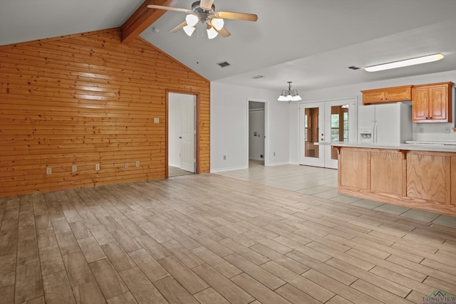 unfurnished living room with french doors, wooden walls, light hardwood / wood-style floors, ceiling fan with notable chandelier, and vaulted ceiling with beams