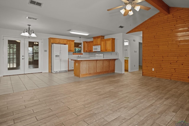 kitchen with white appliances, wood walls, french doors, decorative light fixtures, and ceiling fan with notable chandelier