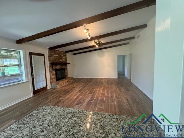 unfurnished living room featuring beam ceiling and a fireplace