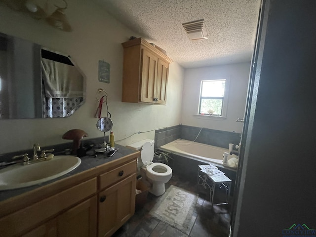 bathroom with a tub, vanity, a textured ceiling, and toilet