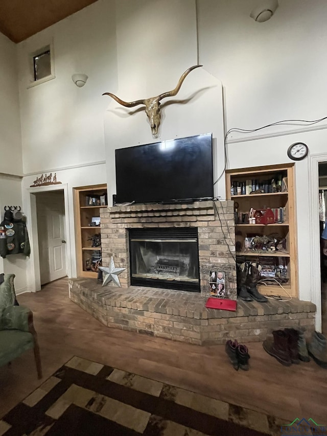 unfurnished living room with carpet, built in shelves, a brick fireplace, and a high ceiling