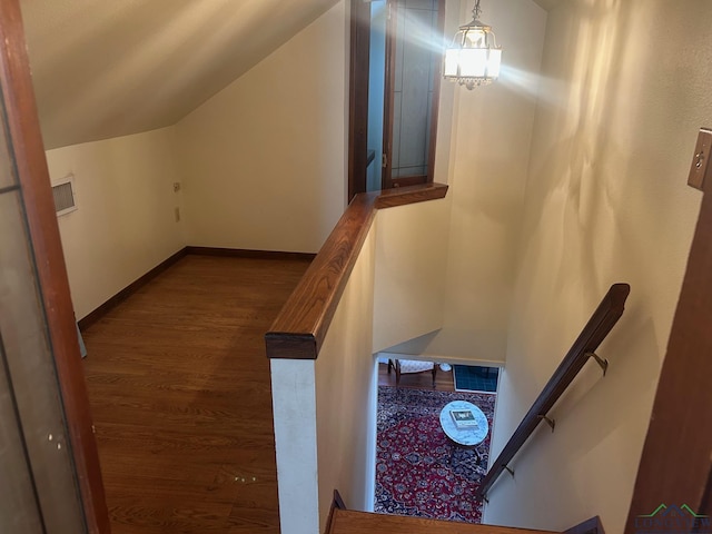 stairs featuring wood-type flooring and vaulted ceiling