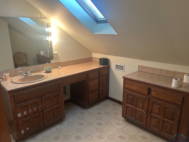 bathroom with vanity, vaulted ceiling with skylight, and toilet