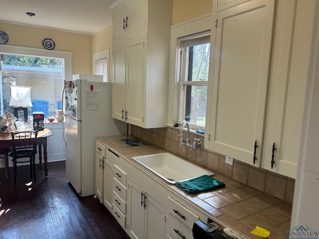 kitchen featuring white cabinetry, tile counters, sink, and a wealth of natural light