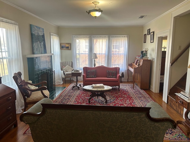 living room featuring a tile fireplace, crown molding, and hardwood / wood-style floors