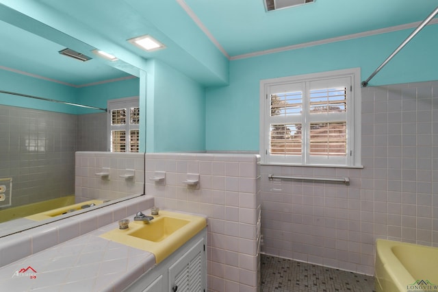 bathroom with vanity, tiled shower / bath combo, tile walls, and crown molding