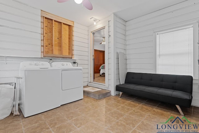 clothes washing area with wood walls, washing machine and clothes dryer, and a ceiling fan