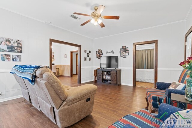 living room featuring ceiling fan, wood finished floors, visible vents, and crown molding