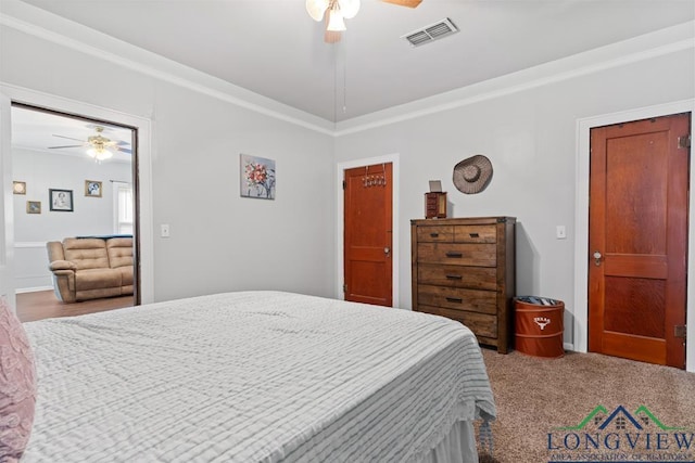 carpeted bedroom with ornamental molding, visible vents, and a ceiling fan