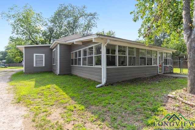 rear view of property with a yard, driveway, fence, and a sunroom